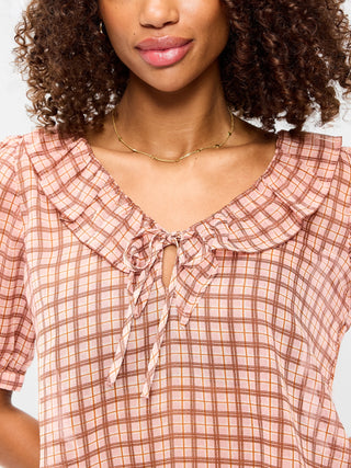 Blusa de gasa con cuello con volantes y lazo en el frente.